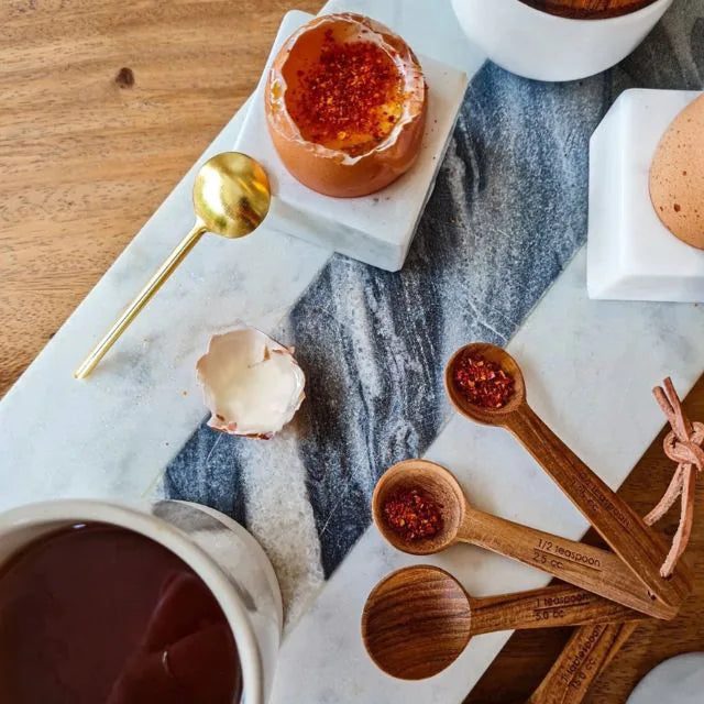 Planche avec un oeuf, des cuillères en bois et un chocolat chaud