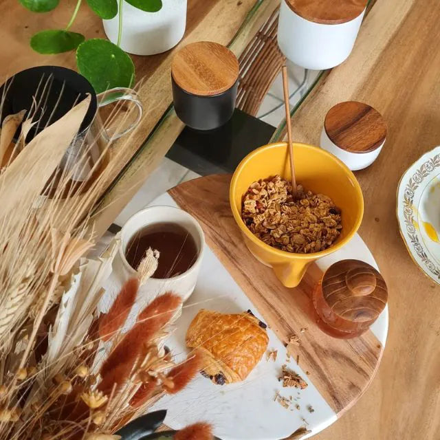 Planche avec un bol de céréales, un chocolat chaud, du miel et une chocolatine