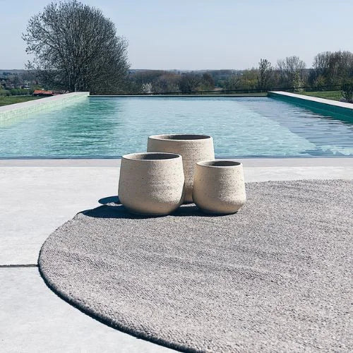 3 bougies d'extérieure blanche posé sur une table au bord de la piscine