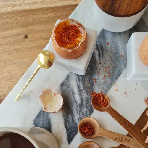 Coquetier avec un oeuf ouvert sur une table et ses cuillères