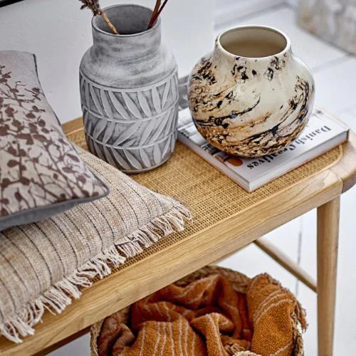 Coussin en coton avec des franges posé sur un table