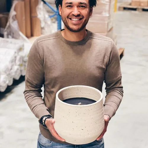 Homme tenant une grande bougie d'extérieure blanche avec la cire noire