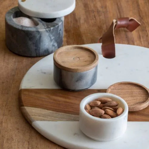 planche ronde en marbre blanc et bois sur une table avec des pots posés dessus
