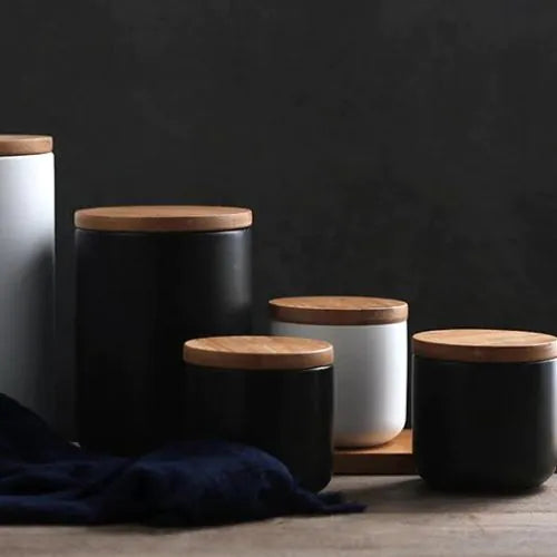 lot de pots en grès noir et blanc avec leurs couvercles fermé sur un fond sombre