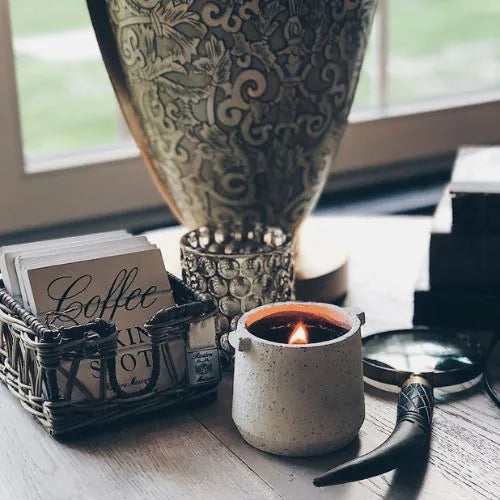 bougie d'intérieure blanche avec la cire noire sur un bureau à côté d'un vase