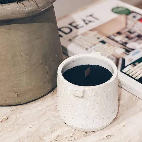 bougie d'intérieure blanche avec la cire noire à côté d'un magazine