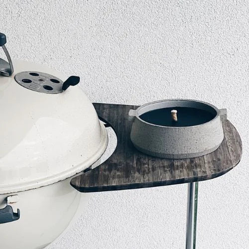 bougie d'extérieure grise avec la cire noire à côté d'un barbecue