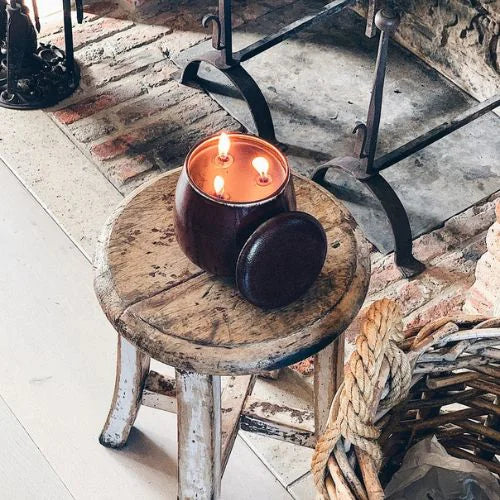 bougie d'intérieure rouge à 3 mèches allumé sur un tabouret en bois