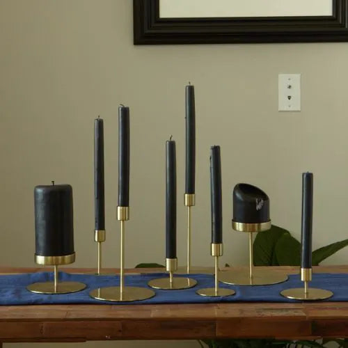Bougeoirs dorés mis en scène avec des bougies noires sur une table