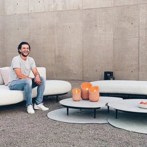 trois bougies orange allumés sur une table basse à côté d'un homme souriant