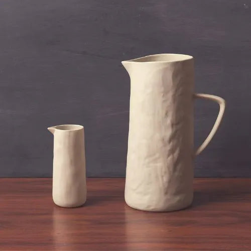 deux pichets en grès blanc sur une table en bois