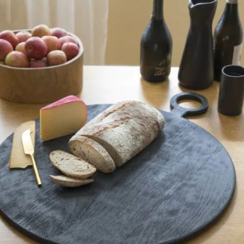 grande planche ronde noire avec du fromage du pain et un couteau à fromage