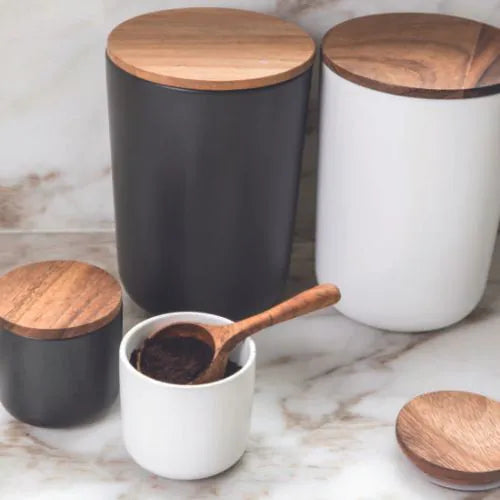 plusieurs pots en grès blanc avec leurs couvercles en bois d'acacia sur un plan en marbre