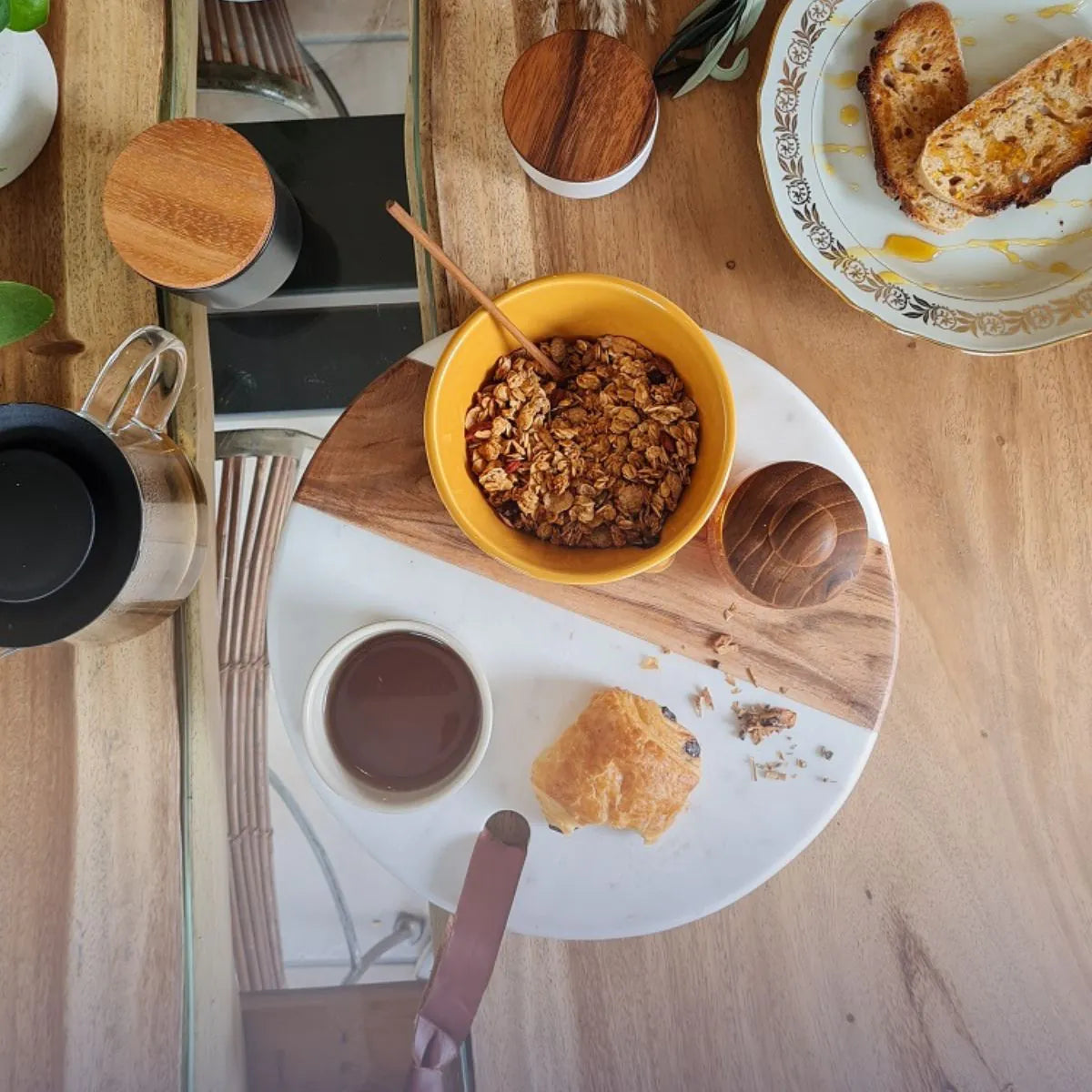planche avec des céréales, du miel, une chocolatine et un chocolat chaud sur une table