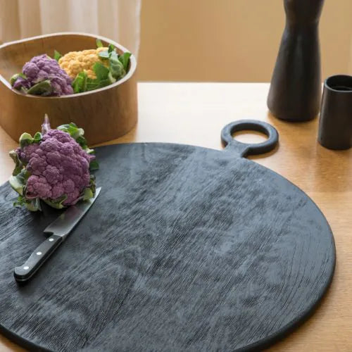 planche ronde noire sur une table avec fleurs décoratives