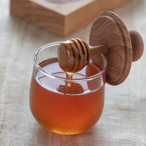 pot de miel en verre avec son couvercle en teck ouvert montrant le miel