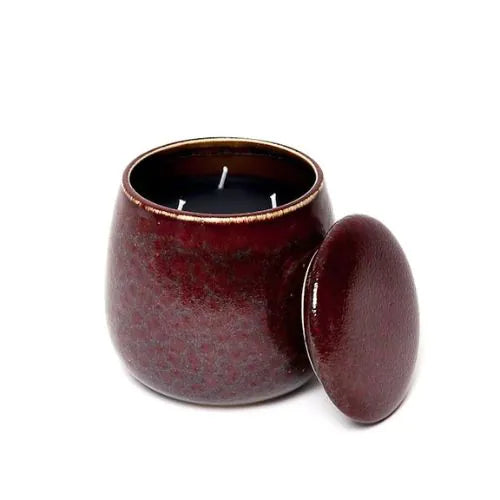 bougie d'intérieure rouge en céramique à trois mèches avec sa cire noire et son couvercle ouvert sur fond blanc